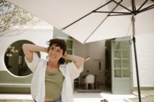 a woman standing under an umbrella smiling at the camera